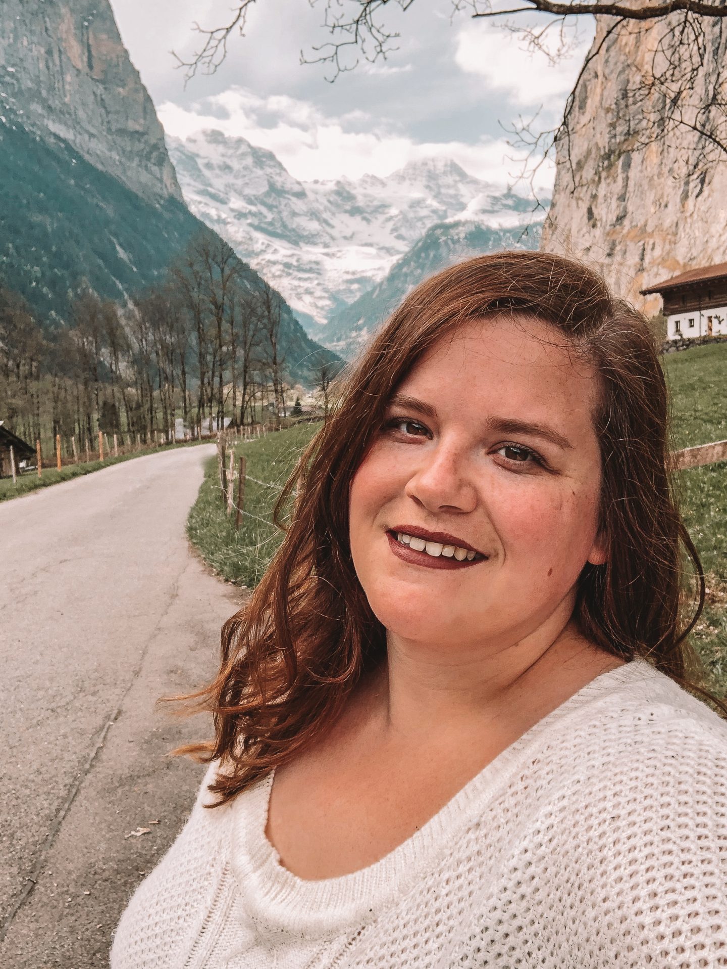 A solo female traveler with the Swiss Alps in the background while in Lauterbrunnen, Switzerland.