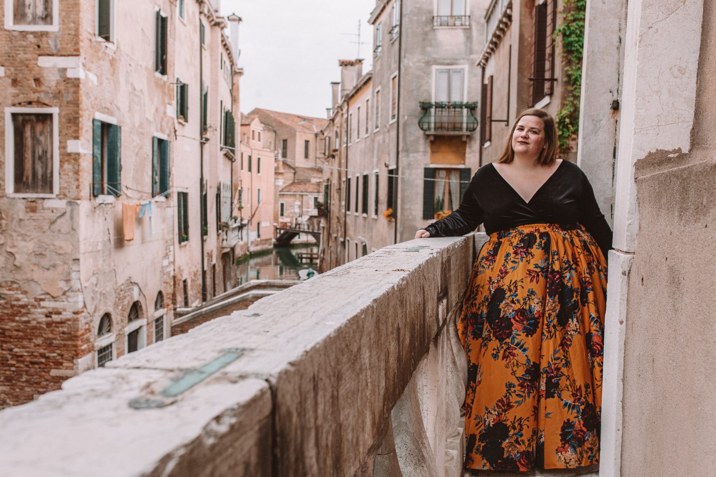 A fashionable plus-sized female posing on a balcony overlooking a canal in Venice, Italy
