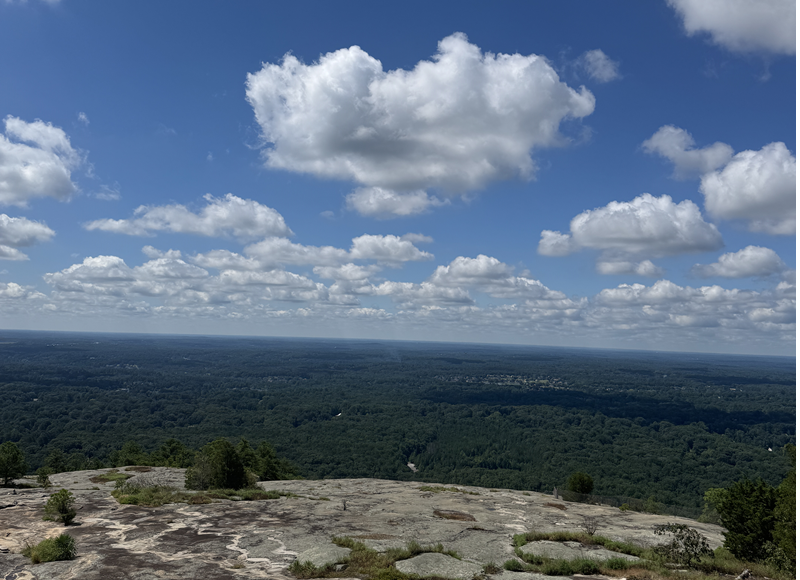 View from top of Stone Mountain, GA. Mountain at the bottom and trees and scenic view. A blue sky with clouds, Weekend Getaway to Stone Mountain
